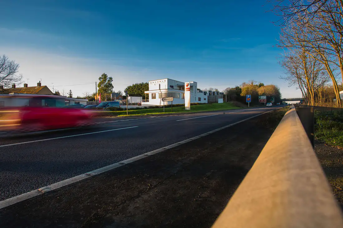 ArcHaus in the distance from the roadside, with a car blurred as it passes