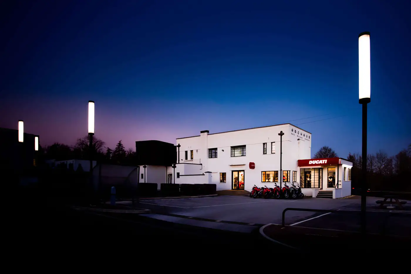 ArcHaus at night, with floodlit lamp posts and the building lit from within